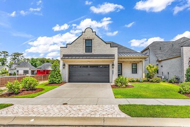 French country home featuring a standing seam roof, driveway, a garage, brick siding, and metal roof