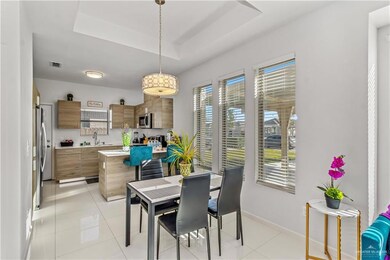 Tiled dining space featuring a raised ceiling, a healthy amount of sunlight, and sink
