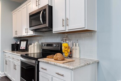 Kitchen featuring appliances with stainless steel finishes, white cabinetry, and backsplash