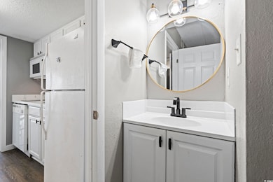 Bathroom with wood finished floors, a textured ceiling, vanity, and a textured wall