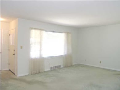 The living room offers a large triple window for a