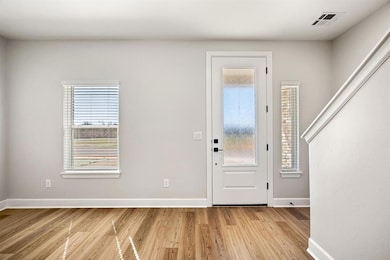 The welcoming entryway is filled with natural light, offering direct access to the second floor and access to a front flex room—perfect for an office or play area.