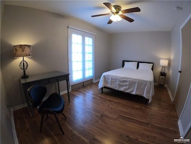 Bedroom with dark wood finished floors, baseboards, and ceiling fan