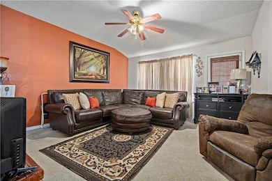 Carpeted living room with a ceiling fan, vaulted ceiling, and a textured ceiling
