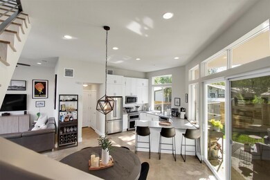 A bright, open-concept living and dining area with 14’ ceilings, polished concrete floors, and walls of windows that bring the outdoors in. Perfect for entertaining, relaxing, or enjoying the seamless flow from the kitchen to the private patio.