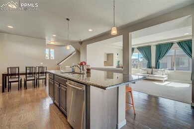Kitchen featuring light hardwood / wood-style flooring, stone counters, sink, dishwashing machine, and pendant lighting