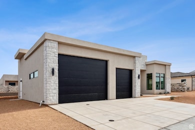 Modern home with a garage, stucco siding, driveway, and stone siding
