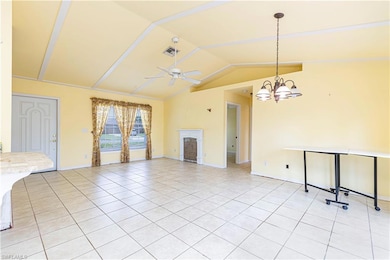 Unfurnished living room featuring light tile patterned floors, vaulted ceiling, ceiling fan, baseboards, and a fireplace