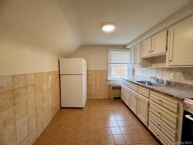 Kitchen featuring freestanding refrigerator, light tile patterned floors, tile walls, radiator heating unit