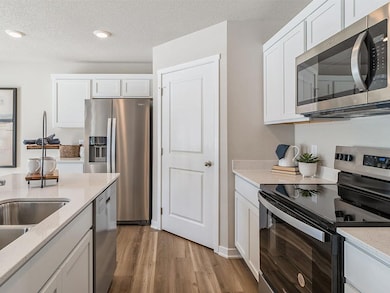 Side view of kitchen with stainless-steel appliances and quartz countertops.  A corner pantry is a must!  Model home shown.