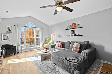Living room featuring light wood finished floors, lofted ceiling, and ceiling fan