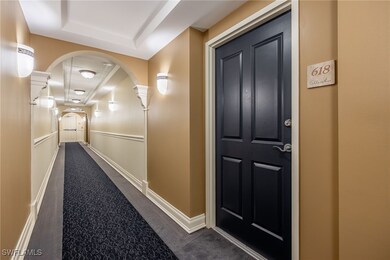 Hall featuring a raised ceiling, dark carpet, and