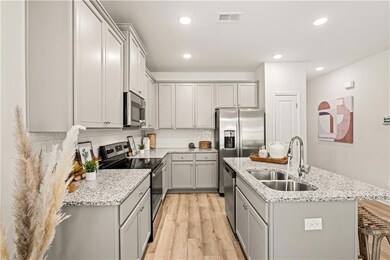 Kitchen featuring sink, light stone counters, appl