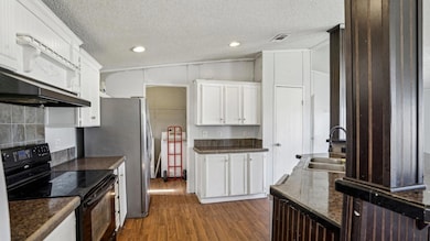 Kitchen with white cabinets, dark countertops, dar