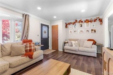 Living room with dark wood finished floors, recessed lighting, and ornamental molding