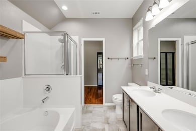 Bathroom featuring a bath, a stall shower, toilet