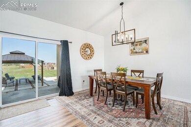 Dining room with light wood finished floors, a chandelier, and high vaulted ceiling