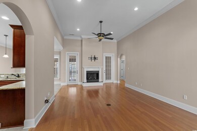 Unfurnished living room featuring crown molding, baseboards, arched walkways, light wood finished floors, and a ceiling fan