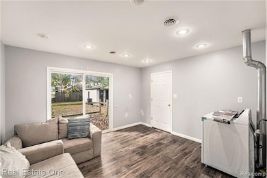 Living room featuring dark wood-type flooring, washer / dryer, and recessed lighting