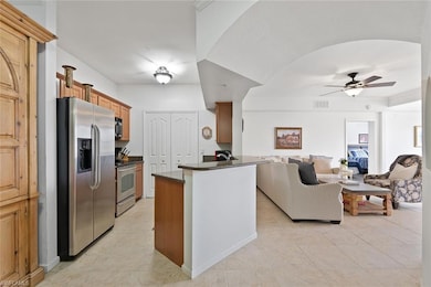 Kitchen with stainless steel appliances, open floor plan, brown cabinets, a ceiling fan, and light tile patterned floors