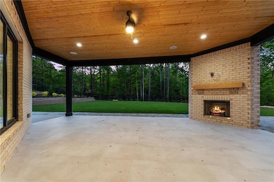 View of patio / terrace with an outdoor brick fireplace and a carport
