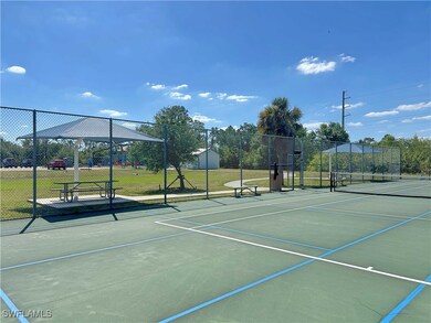View of tennis court with fence and community bask