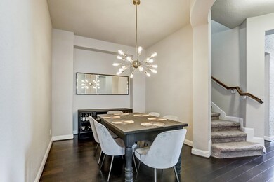 Formal dining is conveniently located and features handsome dark wood floors and a beautiful modern chandelier.