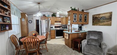Kitchen featuring lofted ceiling, white appliances, ceiling fan, sink, and decorative light fixtures