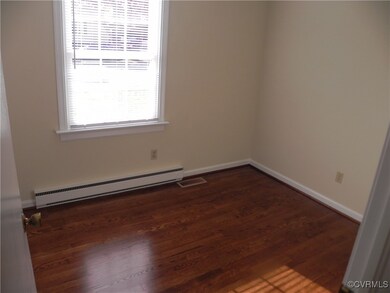 Empty room featuring dark hardwood / wood-style floors and a baseboard radiator