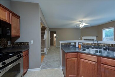Kitchen featuring stainless steel gas range oven, dark countertops, a fireplace, black microwave, and ceiling fan