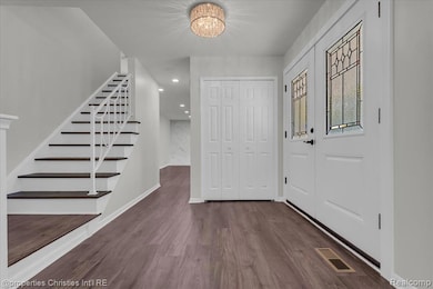 Entryway with stairs, a chandelier, dark wood-style flooring, and recessed lighting