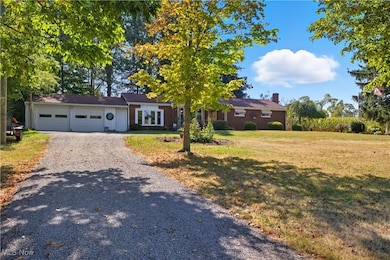 Ranch-style home with a chimney, a front lawn, driveway, a garage, and brick siding