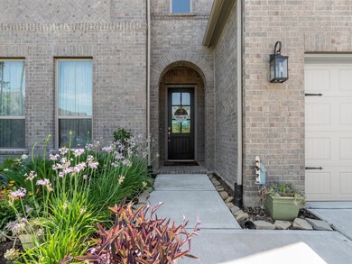 Brick elevation featuring an arched entryway and low maintenance landscaping.