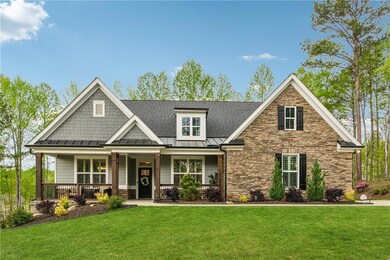 Craftsman-style house with a standing seam roof, stone siding, a front lawn, roof with shingles, and covered porch