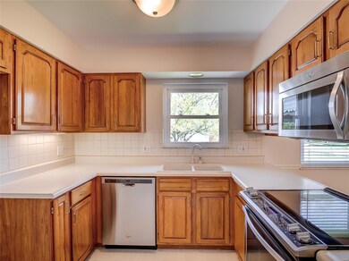 A view of the kitchen with stainless appliances and tiled back splash.