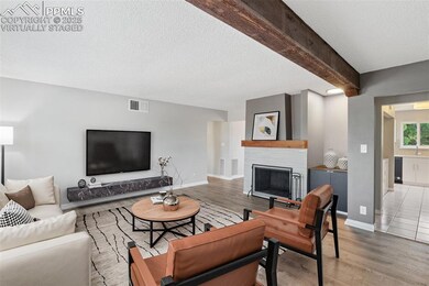Virtually Staged - Living room featuring wood finished floors, a textured ceiling, a fireplace, and beam ceiling