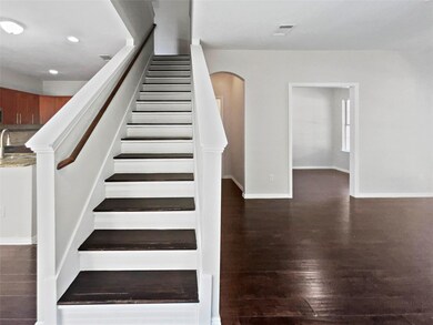 Stairway with wood finished floors, arched walkways, and recessed lighting