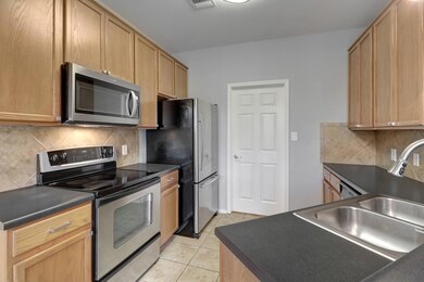 Bright main-floor kitchen featuring black and stainless steel appliances, recessed lighting, and natural light from surrounding windows—easily accessible from both the garage and main living area.