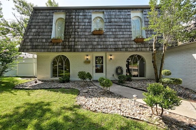 View of front of home with mansard roof, brick siding, and a front lawn