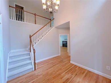 Stairs featuring wood finished floors, a chandelier, baseboards, and a towering ceiling