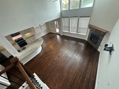 Unfurnished living room featuring a fireplace, wood finished floors, and a high ceiling