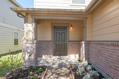 This welcoming front porch with a combination of brick and siding, featuring a neatly landscaped garden bed and a well-lit entrance.