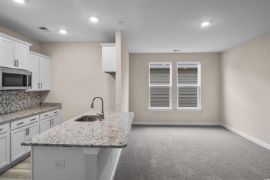 Kitchen with white cabinetry, light stone countert