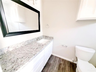 Bathroom featuring baseboards, wood finished floors, toilet, and vanity