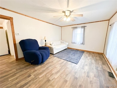 Living area with wood finished floors, ornamental molding, and a ceiling fan