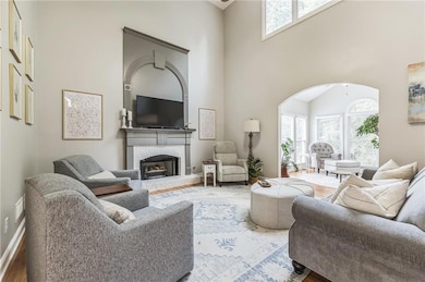 Living room featuring a high ceiling, plenty of natural light, wood finished floors, and a fireplace