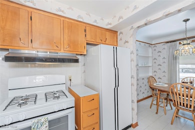 Kitchen featuring white appliances, light countertops, under cabinet range hood.