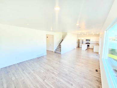 Unfurnished living room with light wood finished floors, stairway, and recessed lighting
