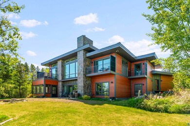 Rear view of house with a balcony and a lawn