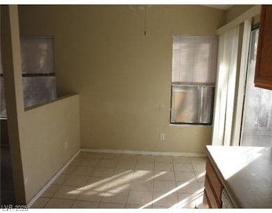 Unfurnished dining area with light tile patterned floors and baseboards